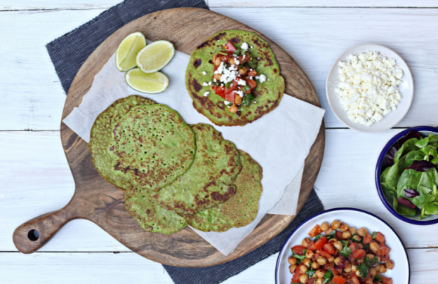 board with spinach pancakes on it that are green with small bowls beside the board with toppings